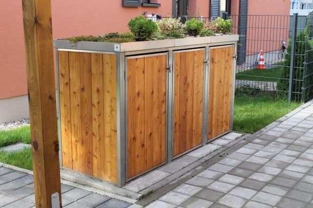 Die Ansicht zeigt eine komplett natürliche Mülltonnenbox mit Lärchen Lattung. Diese wird im Laufe der Jahre silbrig grau verwittern. Mülltonnenbox Holz vertikale Lattung